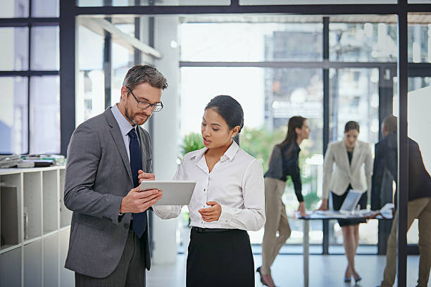 Shot of a businessman showing  something to his female colleague while they stand outside the boardroom